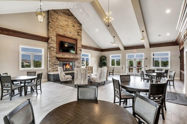 dining area featuring light wood-type flooring, a chandelier, high vaulted ceiling, and a fireplace