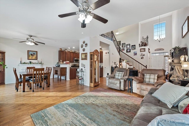 living room featuring a towering ceiling, ceiling fan, and light hardwood / wood-style flooring