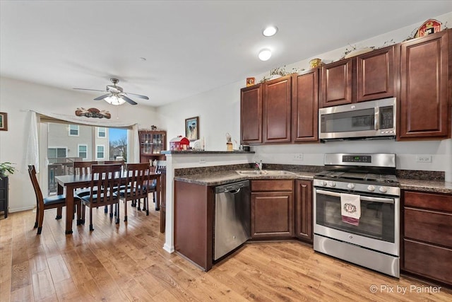 kitchen featuring appliances with stainless steel finishes, light hardwood / wood-style floors, kitchen peninsula, ceiling fan, and sink