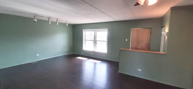 spare room with rail lighting, ceiling fan, and dark hardwood / wood-style floors