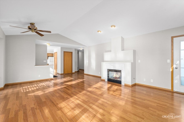 unfurnished living room featuring vaulted ceiling, ceiling fan, a high end fireplace, and light hardwood / wood-style flooring