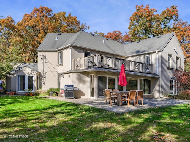 rear view of property featuring a balcony, a yard, and a patio area