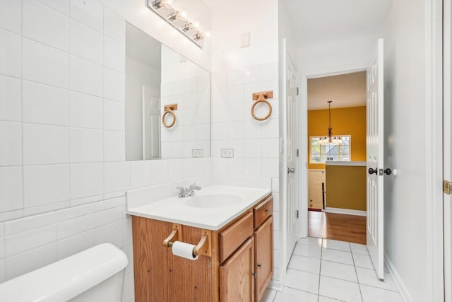 bathroom featuring toilet, tile patterned flooring, a notable chandelier, tile walls, and vanity