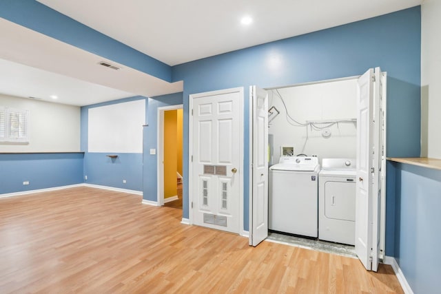 laundry area featuring washer and dryer and light hardwood / wood-style flooring