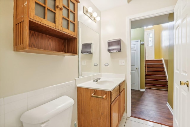 bathroom with toilet, vanity, tile patterned floors, and tile walls