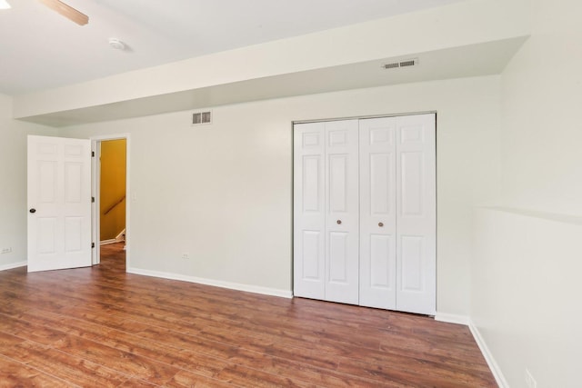 unfurnished bedroom featuring ceiling fan, dark hardwood / wood-style flooring, and a closet