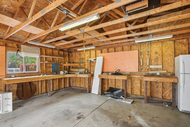 garage with white refrigerator and a workshop area