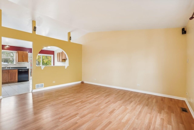 unfurnished living room with sink, light wood-type flooring, and lofted ceiling