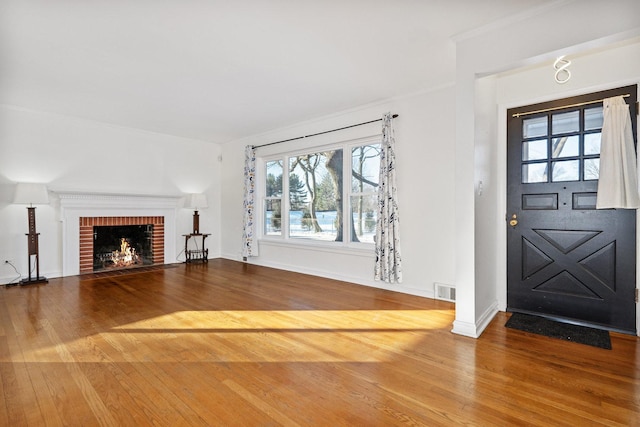 foyer entrance featuring wood-type flooring, crown molding, and a fireplace