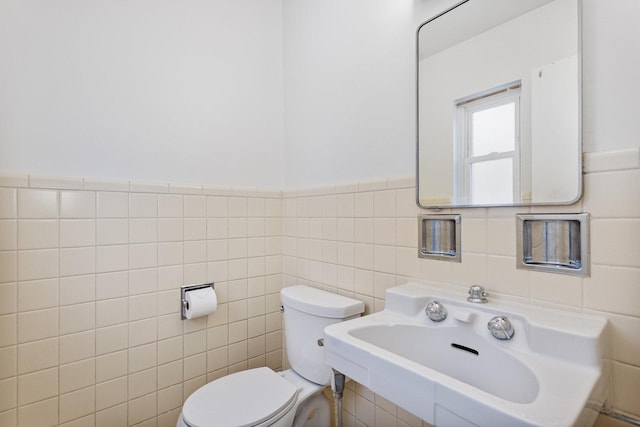 bathroom with toilet, tile walls, and sink