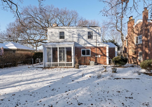 snow covered property featuring a sunroom