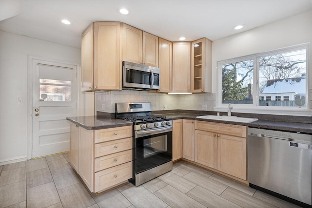 kitchen with tasteful backsplash, light brown cabinetry, appliances with stainless steel finishes, and sink