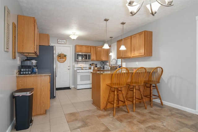 kitchen with a kitchen bar, a textured ceiling, hanging light fixtures, kitchen peninsula, and stainless steel appliances