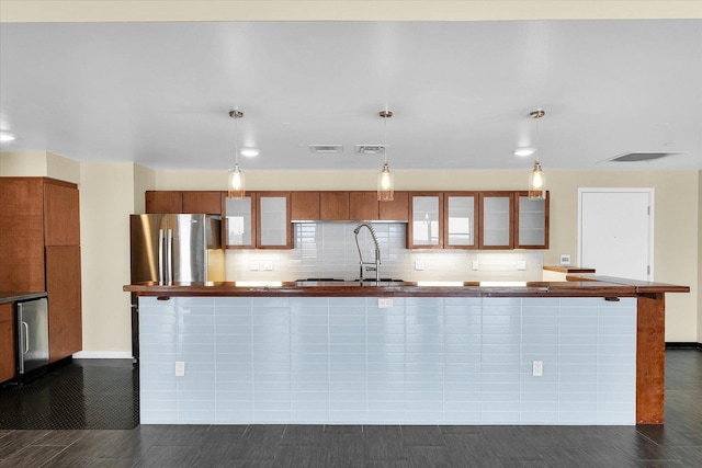 kitchen featuring pendant lighting, sink, tasteful backsplash, and stainless steel refrigerator