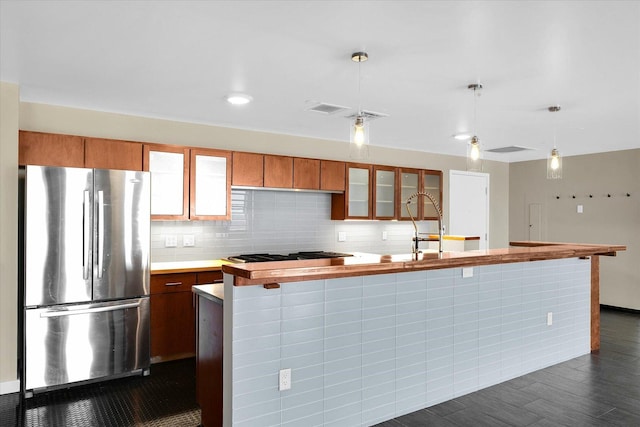 kitchen featuring appliances with stainless steel finishes, dark hardwood / wood-style floors, an island with sink, pendant lighting, and backsplash