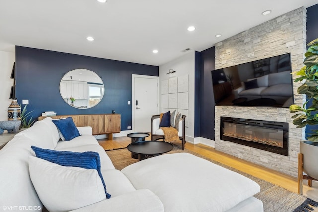 living room featuring light wood-type flooring and a stone fireplace