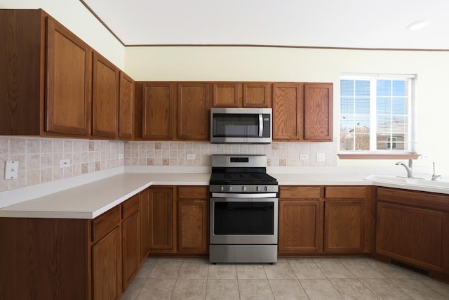 kitchen featuring sink, backsplash, stainless steel appliances, and light tile patterned flooring