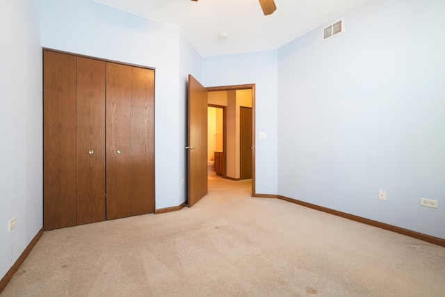 unfurnished bedroom with ceiling fan, a closet, and light carpet