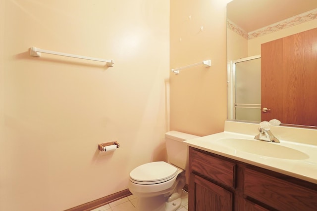 bathroom featuring toilet, vanity, tile patterned flooring, and a shower with door