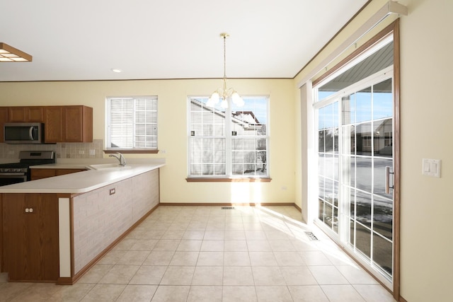 kitchen with pendant lighting, appliances with stainless steel finishes, an inviting chandelier, sink, and kitchen peninsula