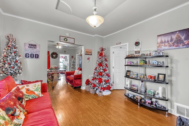 living room with hardwood / wood-style flooring, ceiling fan, and ornamental molding