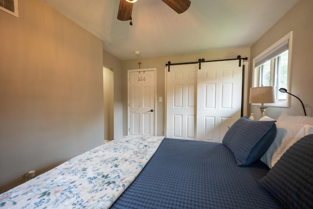 bedroom featuring ceiling fan and a barn door