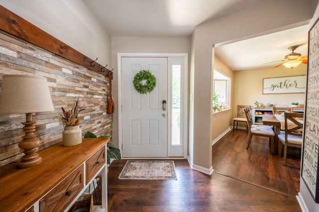 entrance foyer with dark wood-type flooring, wood walls, and ceiling fan