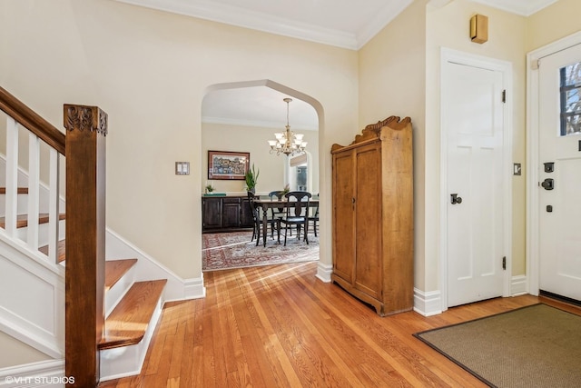 foyer entrance featuring light hardwood / wood-style floors, crown molding, and a chandelier