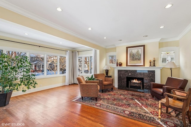 living room featuring wood-type flooring, a high end fireplace, and ornamental molding