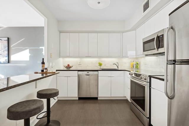 kitchen featuring white cabinets, backsplash, appliances with stainless steel finishes, and sink