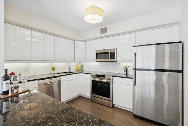 kitchen with sink, white cabinetry, backsplash, and stainless steel appliances