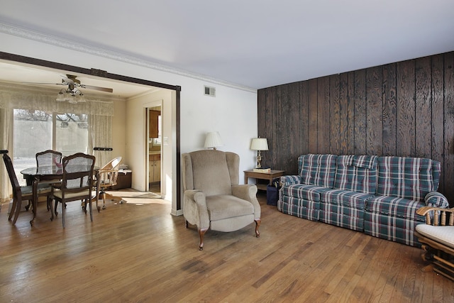 living room featuring hardwood / wood-style flooring, ornamental molding, and ceiling fan