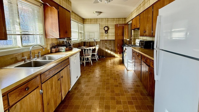 kitchen with sink, white appliances, and wooden walls