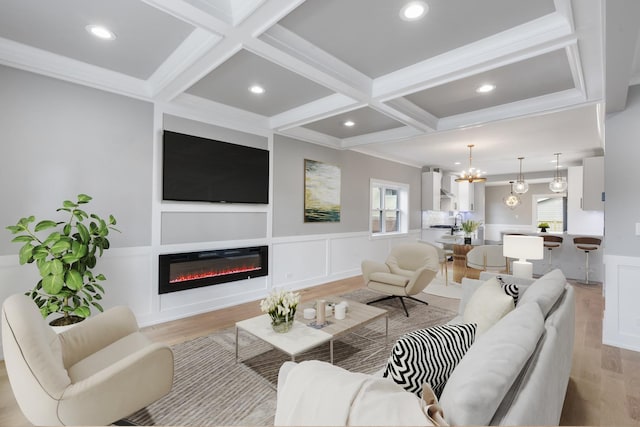 living room with coffered ceiling, crown molding, beam ceiling, light hardwood / wood-style flooring, and an inviting chandelier