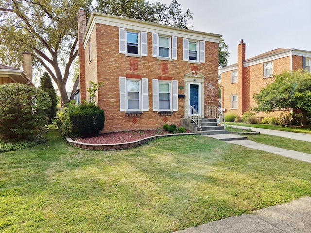 view of front facade featuring a front yard, a chimney, and brick siding