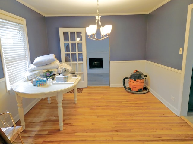 dining area with crown molding, a fireplace, a notable chandelier, and wood finished floors