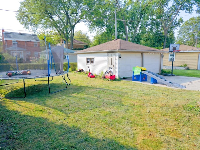 view of yard featuring a garage, a trampoline, and an outdoor structure