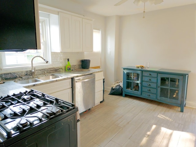 kitchen featuring a sink, light wood-type flooring, backsplash, black range with gas stovetop, and dishwasher