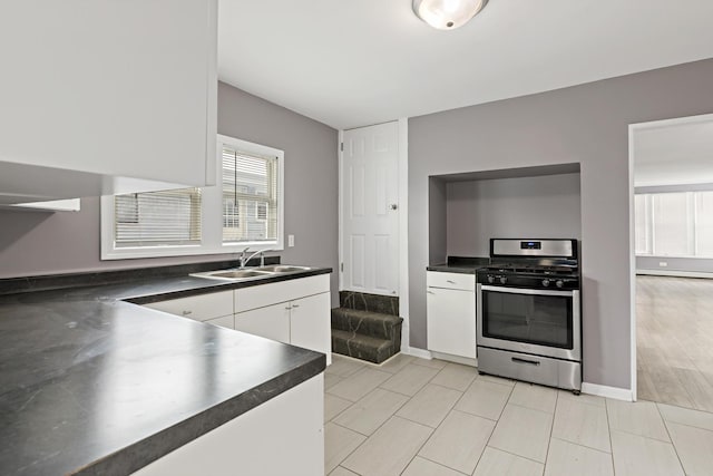 kitchen featuring stainless steel gas stove, sink, and white cabinetry