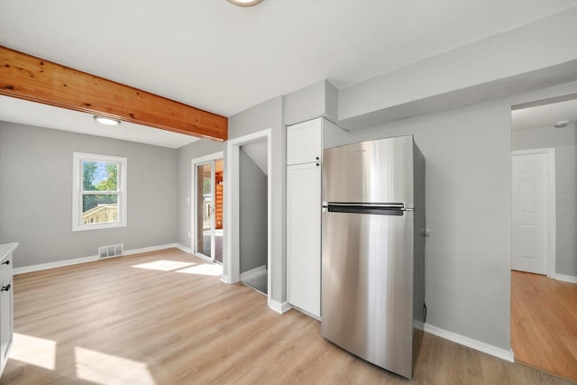 kitchen featuring light hardwood / wood-style flooring, white cabinetry, beamed ceiling, and stainless steel refrigerator