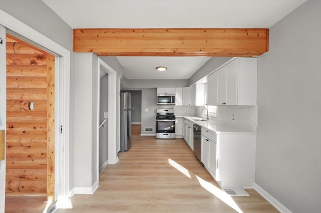 kitchen featuring white cabinets, appliances with stainless steel finishes, light hardwood / wood-style flooring, and sink