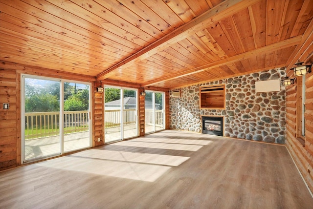 unfurnished living room with a fireplace, beamed ceiling, hardwood / wood-style floors, a wall mounted AC, and wood ceiling