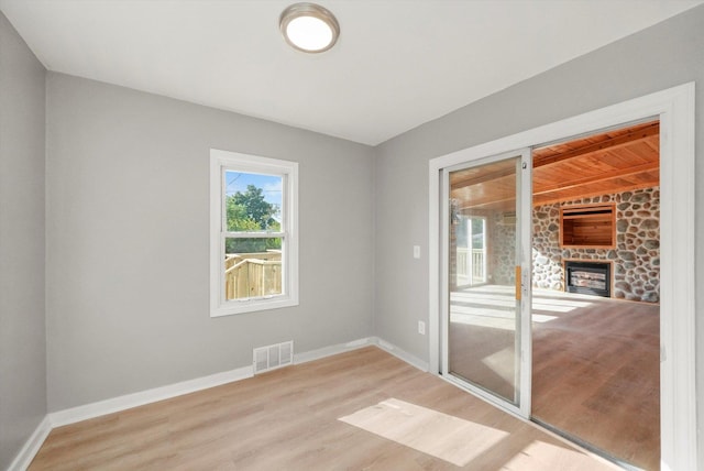 unfurnished room featuring light wood-type flooring and a stone fireplace