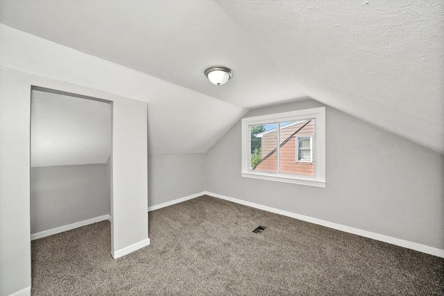 bonus room with lofted ceiling, a textured ceiling, and carpet