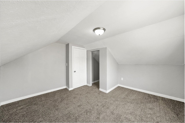 bonus room featuring lofted ceiling, a textured ceiling, and dark carpet