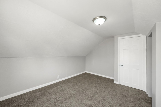 additional living space featuring dark carpet and vaulted ceiling