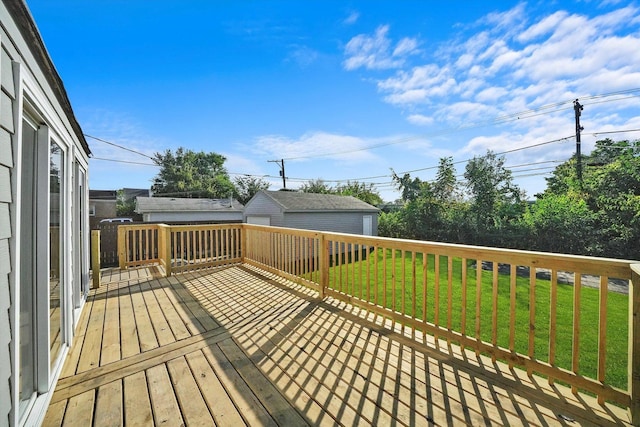 wooden deck with a lawn, a garage, and an outbuilding