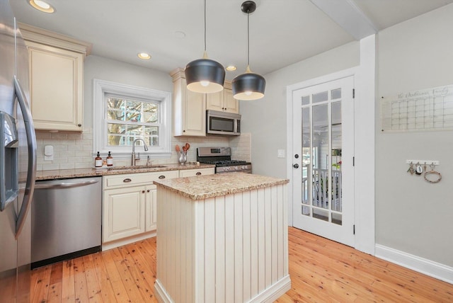 kitchen with a center island, decorative light fixtures, stainless steel appliances, tasteful backsplash, and sink