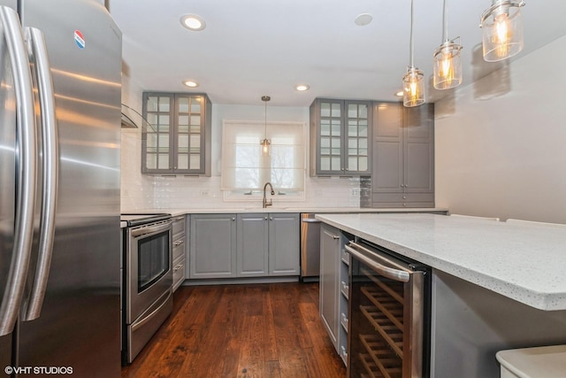 kitchen featuring pendant lighting, beverage cooler, gray cabinets, dark hardwood / wood-style flooring, and appliances with stainless steel finishes