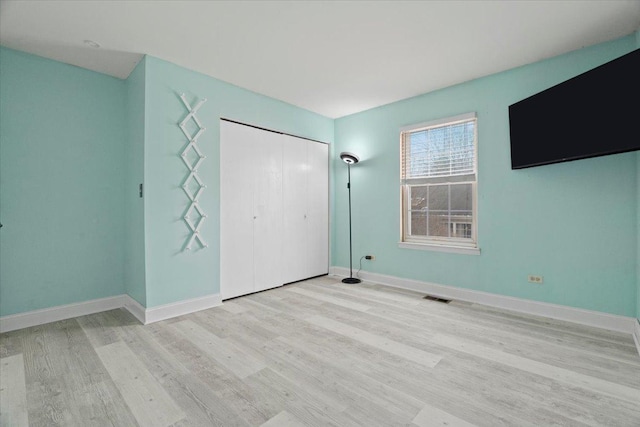 unfurnished bedroom with light hardwood / wood-style floors and a closet